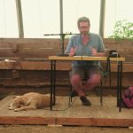 Jean-Chridstophe Goddard donnant une conférence avec un chien couché à ses pieds